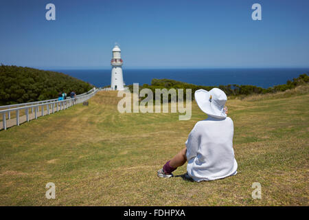 Jeune femme assise sur les herbages à à lighthouse Banque D'Images