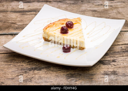 Tranche de gâteau au fromage avec cerise sur le plat blanc. Fond dessert Restaurant Banque D'Images