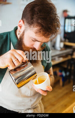 Barista pouring lait en tasse de café au coffee shop Banque D'Images