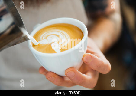 Closeup portrait of barista pouring lait en tasse de café au coffee shop Banque D'Images