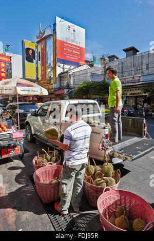 Un vendeur ambulant vérifie les fruits de durian frais d'un lot nouvellement reçu. Route de Yaowarat, Chinatown, Bangkok, Thaïlande. Banque D'Images