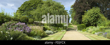 Vue panoramique le long de la frontières herbacées double, au-dessus de la route, vers l'avenue de l'autre côté, du jardin créé par Simon Sainsbury et Stewart Grimshaw à Woolbeding House, West Sussex. Banque D'Images