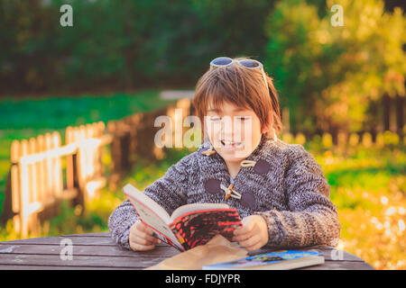 Boy reading book in garden Banque D'Images