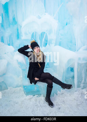 Une très jolie jeune femme est assise sur un trône sculpté dans la glace à la glace dans le château de Hawrelak Park, Edmonton, Alberta, Canada. Banque D'Images