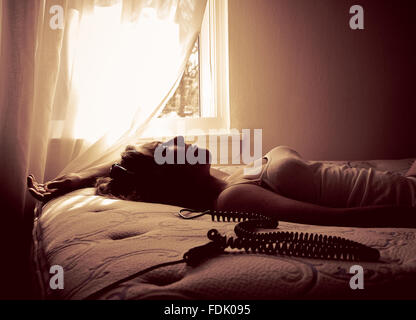Woman lying on bed listening to music with headphones Banque D'Images