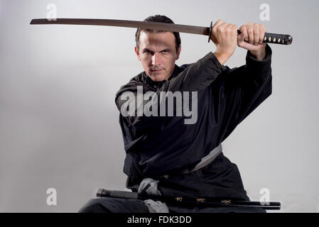 L'homme habillé en tenue de samurai katana en l'air Banque D'Images