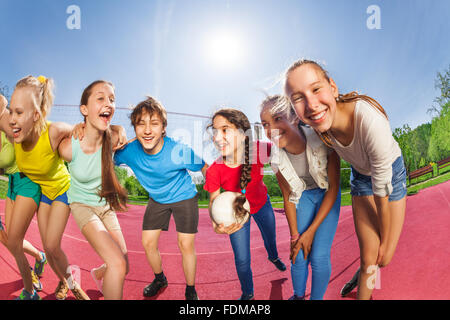 Les adolescents heureux debout sur la cour de jeu de volley-ball Banque D'Images