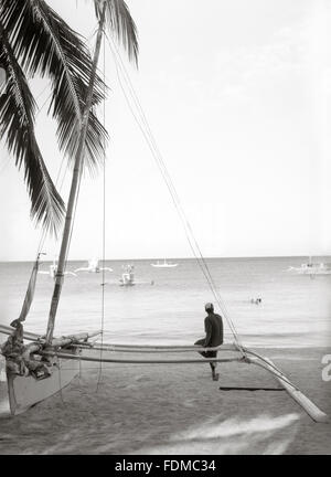 Un homme est assis sur un bateau de pêche sur la plage de Boracay, Philippines, Asie du Sud Est. Banque D'Images