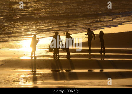 Groupe de personnes sur la plage de Bournemouth, Royaume-Uni, comme le soleil projette des ombres dans le sable Banque D'Images