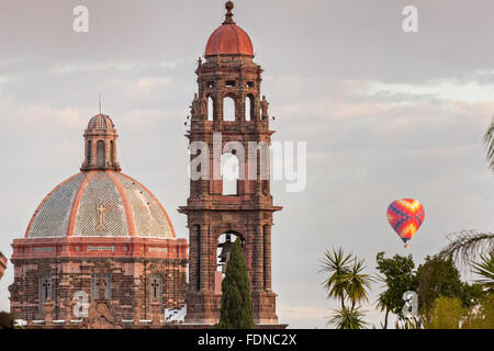 Une montgolfière flotte au-delà de la flèche de l'église de San Francisco et le dôme de l'Église de Las Monjas dans le centre historique de San Miguel de Allende, Mexique. Banque D'Images