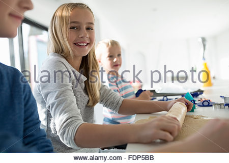 Portrait of smiling girl avec rouleau à pâtisserie baking cookies