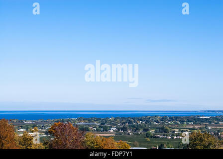 Bord de région semi-rurale par l'eau contre le grand ciel vide expansive en automne. arbres et maisons sont à terre, menant à blue lake. Banque D'Images