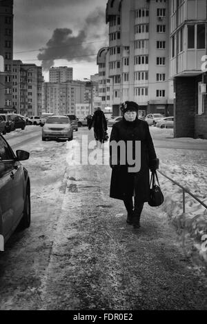 UFA - RUSSIE 26ème décembre 2015 - Femme vêtue d'un manteau de fourrure chaude promenades le long d'un chemin loin d'une cheminée qui ondulent à Oufa, Russ Banque D'Images