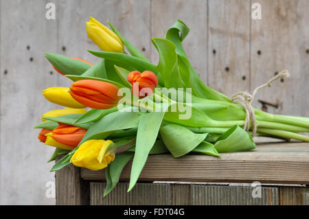 Bouquet de tulipes jaunes et orange sur une boîte en bois Banque D'Images