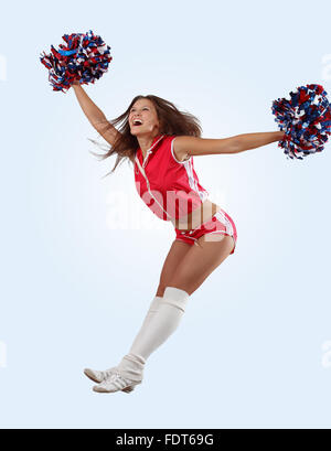 Cheerleader en uniforme saute haut dans les airs isolé sur blanc. Banque D'Images