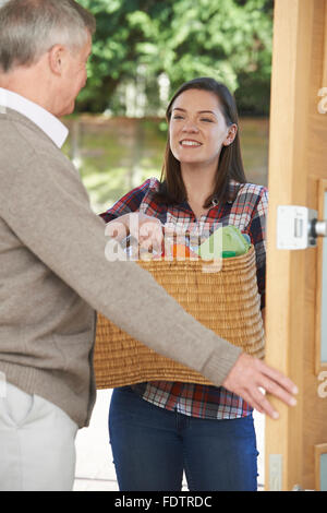 Teenage Girl Doing Shopping pour leurs voisins âgés Banque D'Images