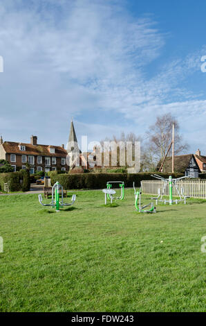 L'équipement d'exercice sur Woodchurch village green, Kent, UK, avec l'église All Saints et de brique et de cottages à l'arrière-plan Banque D'Images