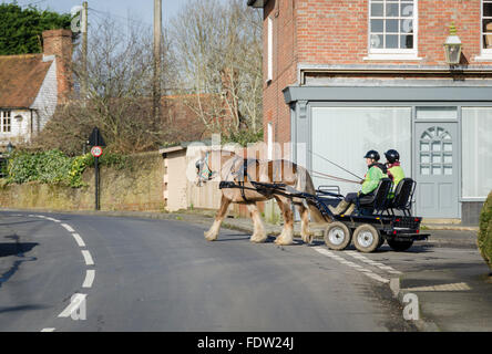 Un cheval tirant deux personnes dans un transport moderne dans la rue, dans le village de Biddenden, Kent Banque D'Images