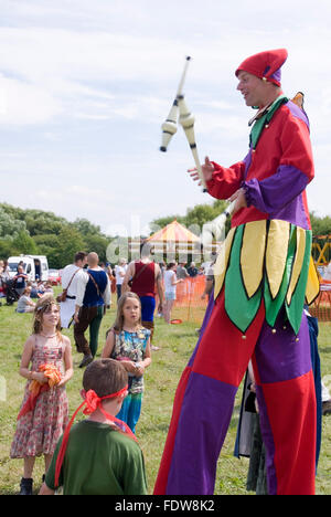 TEWKESBURY, des bureaux extérieurs. UK-11 JUILLET : Jester sur pilotis balades parmi foule juggling le 12 juillet 2014 à Tewkesbury Fête médiévale Banque D'Images