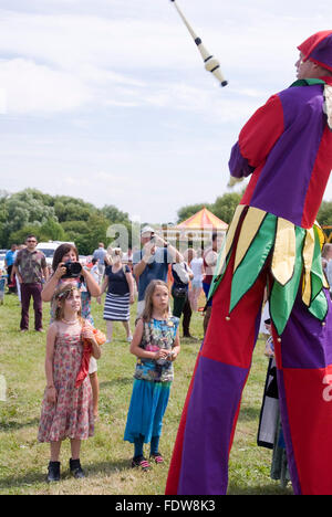 TEWKESBURY, des bureaux extérieurs. UK-11 JUILLET : Jester sur pilotis balades parmi foule juggling le 12 juillet 2014 à Tewkesbury Fête médiévale Banque D'Images