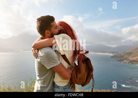 Portrait d'un jeune couple sympathique bénéficiant d'une étreinte romantique en plein air. Jeune homme serrant sa petite amie en se tenant debout sur une colline