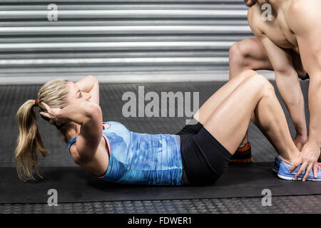 Male trainer assisting woman avec sit ups Banque D'Images