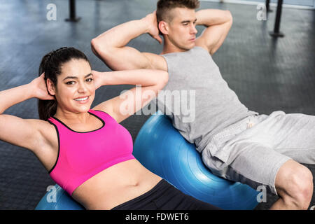 Monter couple doing abdominal crunches on fitness ball Banque D'Images