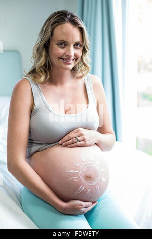 Femme enceinte l'application de la crème sur son ventre Banque D'Images