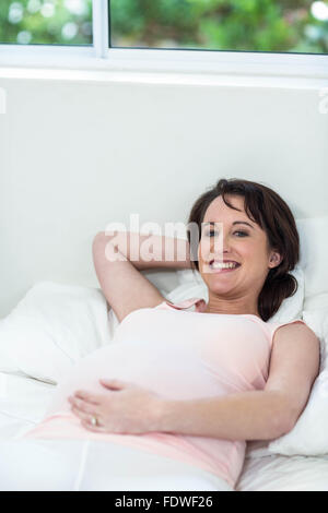 Pregnant woman lying on bed Banque D'Images