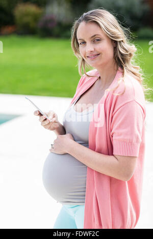 Pregnant woman touching her belly et texting Banque D'Images