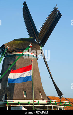 Dutch flag flying & De Zoeker moulin / moulins à vent / moulins à vent / moulins à vent. Zaanse Schans, Hollande, Pays-Bas. Soleil ciel bleu Banque D'Images