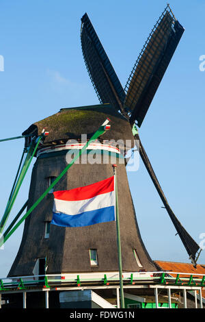 Dutch flag flying & De Zoeker moulin / moulins à vent / moulins à vent / moulins à vent. Zaanse Schans, Hollande, Pays-Bas. Soleil ciel bleu Banque D'Images