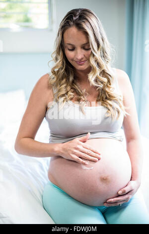 Femme enceinte l'application de la crème sur son ventre Banque D'Images