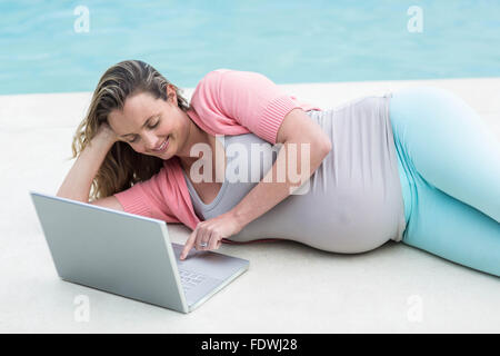 Femme enceinte à l'extérieur de détente using laptop Banque D'Images