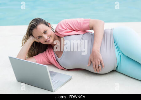 Femme enceinte à l'extérieur de détente using laptop Banque D'Images