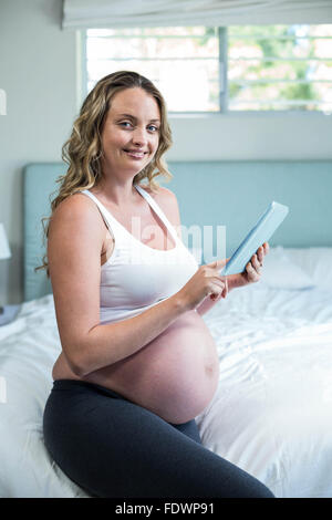 Femme enceinte à l'aide d'un ordinateur tablette Banque D'Images