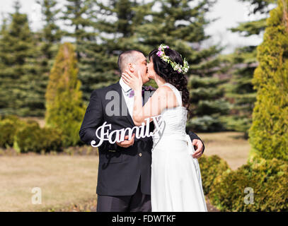 Bride and Groom holding bouquet et famille mot en bois Banque D'Images