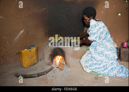 Dame ougandaise de préparer un repas dans une casserole à l'aide de maïs et de feuilles de bananier sur l'efficacité d'une cuisinière. L'Ouganda. Banque D'Images