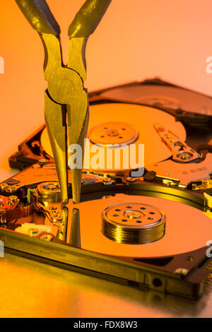 Paire de tenailles bricolage prêts sur un plateau de disque dur dépouillé - métaphore visuelle pour concept d'outils logiciels, outils informatiques. Banque D'Images