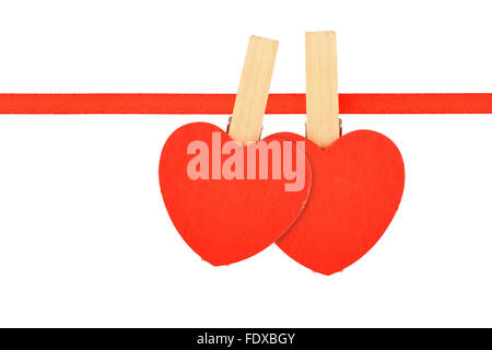 Amour saint valentin modèle, deux coeurs en bois rouge avec des pinces à linge sur ruban textile isolé sur fond blanc Banque D'Images