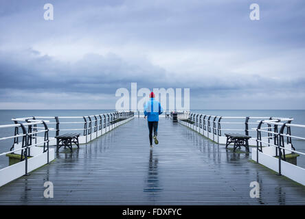 Mature man jogging sur Saltburn pier sous la pluie. Marseille par la mer. Yorkshire du Nord. UK Banque D'Images