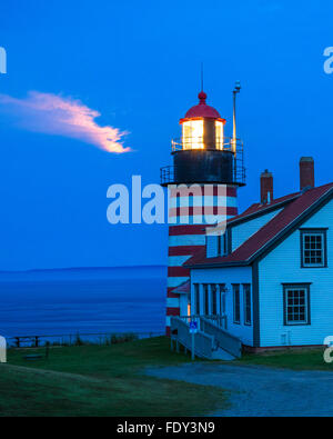 Lubec, Maine : West Quoddy Head Light en soirée avec la lumière provenant de la lune miroitant dans les nuages Banque D'Images