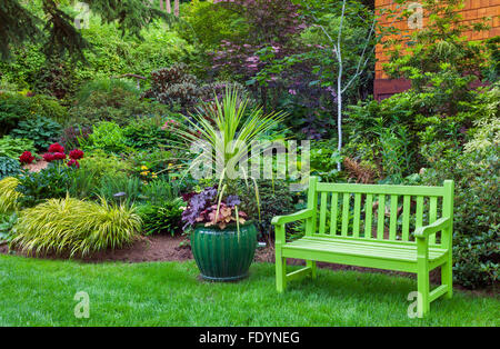 Vashon-Maury Island, WA : un banc et pot Vert chartreuse d'heuchère Heucherella (sp) et palm dans un jardin éternel Banque D'Images