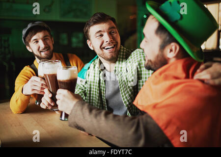 Les jeunes hommes multi-ethnique de boire une bière et se détendre dans un pub Banque D'Images