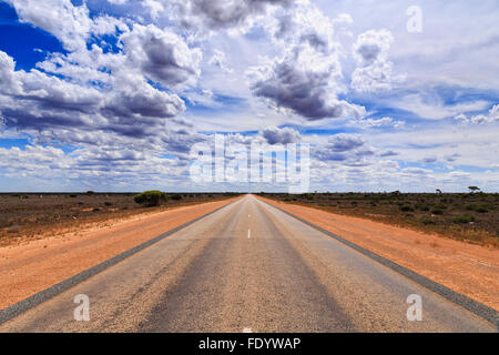 Grande vue en perspective de la route goudronnée en direction de horizon sous un ciel d'été entre le sol rouge des routes avec aucun véhicule Banque D'Images