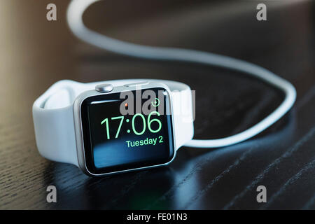 Montre bracelet blanc Apple avec charge et montrant l'heure actuelle. Banque D'Images