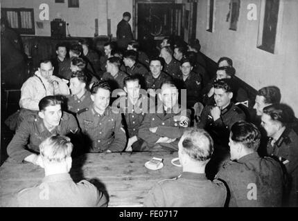 Le tableau de la propagande nazie montre le ministre de l'armement et de la production de guerre Albert Speer (avec le brassard de la swastika) entre les soldats de la Wehrmacht allemande dans un logement militaire sur le front polaire. La photo a été prise en février 1944. Fotoarchiv für Zeitgeschichtee - PAS DE SERVICE DE VIREMENT - Banque D'Images