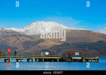 Le Loch Lomond, au Royaume-Uni. 3 Février, 2016. Après les récentes tempêtes et fortes pluies pour la saison, le niveau d'eau à Luss sur le Loch Lomond a surmonté les murs provoquant des inondations locales.Sur la première journée ensoleillée, Tom Wilson et la Géorgie à partir de Londres, en vacances près de Luss, prendre une promenade relaxante pour admirer la neige surmonté Ben Lomond et les eaux calmes du Loch Lomond. Credit : Findlay/Alamy Live News Banque D'Images