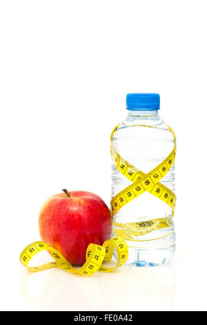 Bouteille de l'eau jaune enveloppé de ruban de mesure avec pomme rouge isolé sur fond blanc avec copie espace Banque D'Images