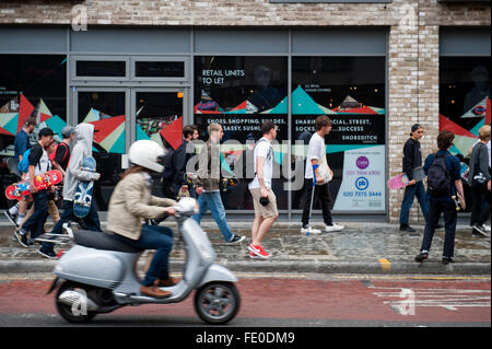 Roulettes âgés de 12-16 à pied passé BOXPARK à Bethnal Green Road à Londres, dans le quartier branché de Shoreditch. Banque D'Images